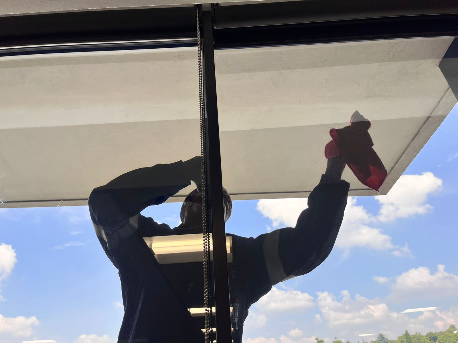Cleaning the top section of a large glass door